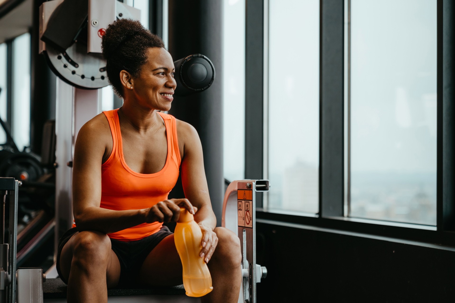 Beautiful fitness woman sitting at gym resting after workout